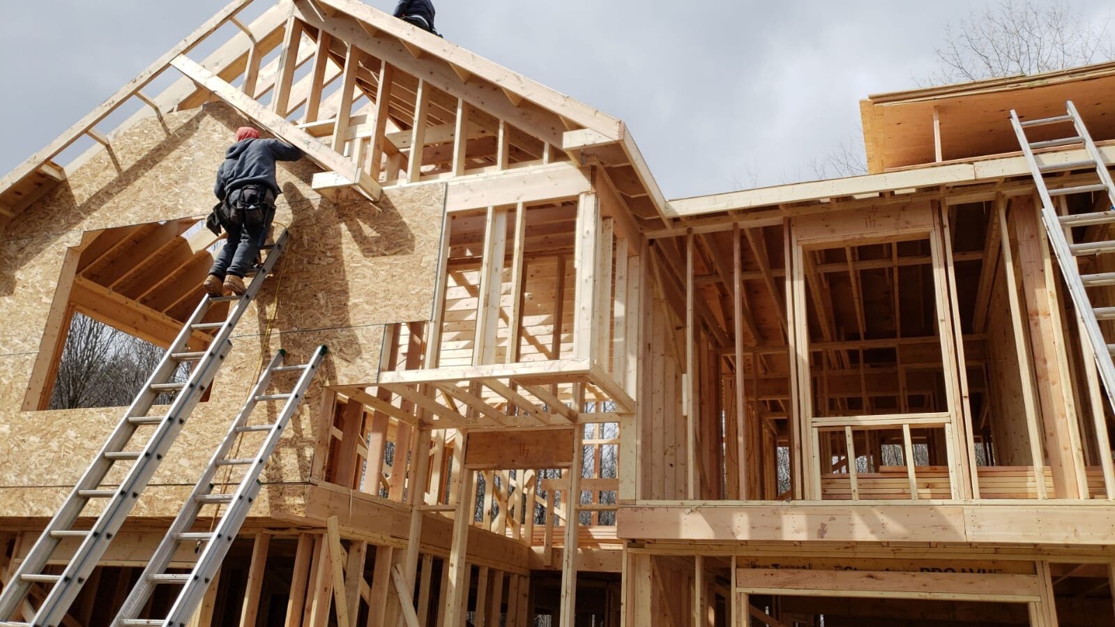 Wilson's crew member on a ladder sheathing a roof gable