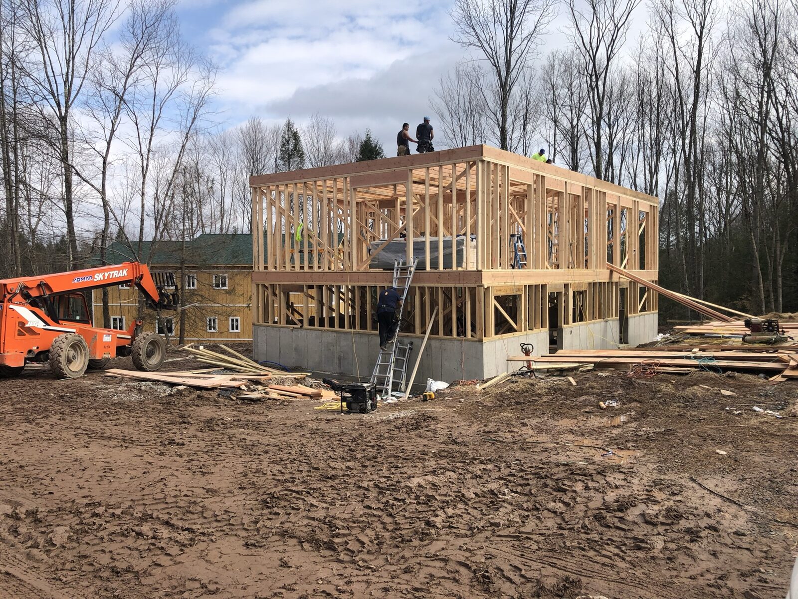 Two crew members standing atop a two-story framed structure during construction