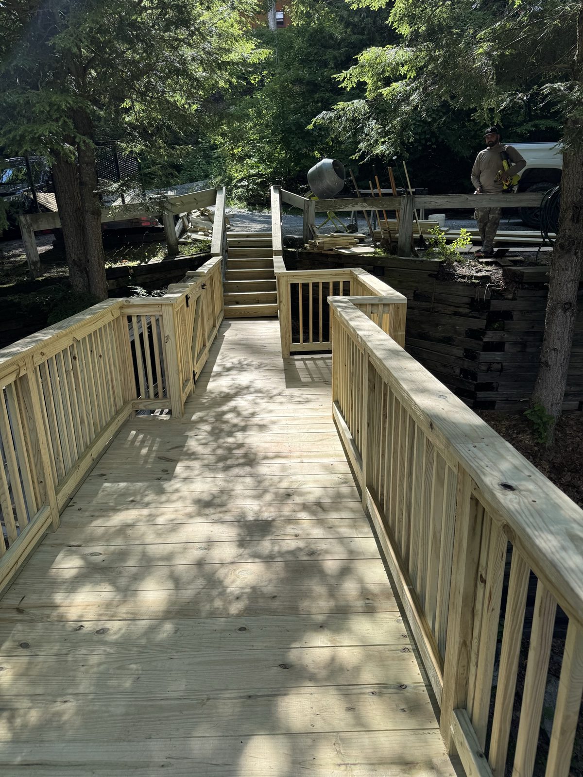 New pressure-treated lakeside walkway under construction leading down toward the water