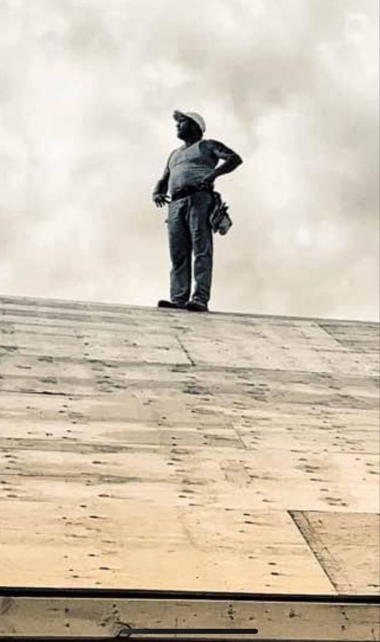 Silhouette of a Wilson's crew member standing atop a newly sheathed roof